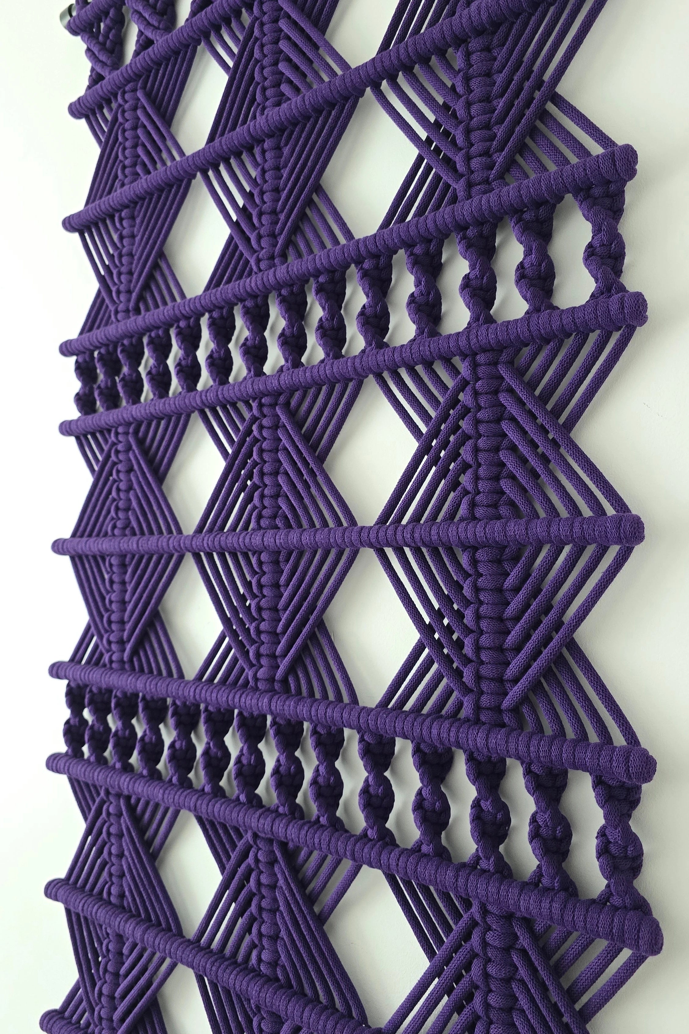 Artystyczna dekoracja ścienna NORDART w kolorze ciemnego fioletu zawieszona na białej ścianie. Geometryczna forma doskonale podkreśla elegancki styl nowoczesnej aranżacji.