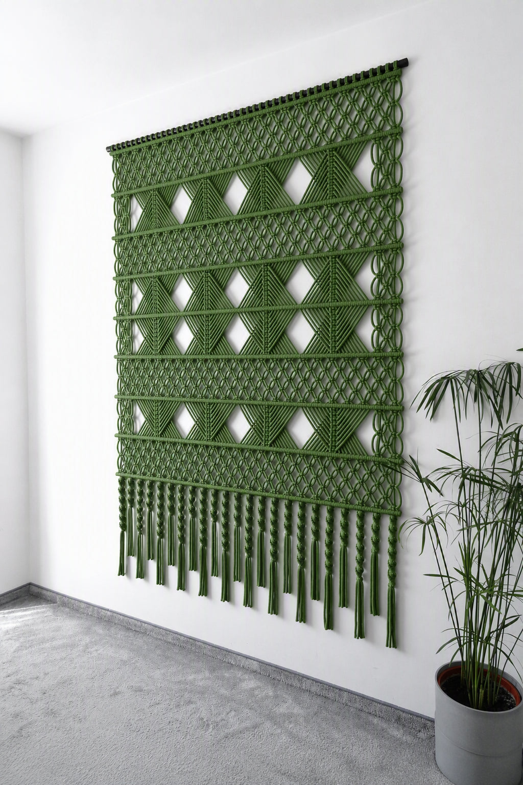 Elegancka zielona dekoracja ścienna NORDART w odcieniu awokado prezentowana w salonie. Geometryczna makrama podkreśla harmonijny i luksusowy charakter wnętrza.