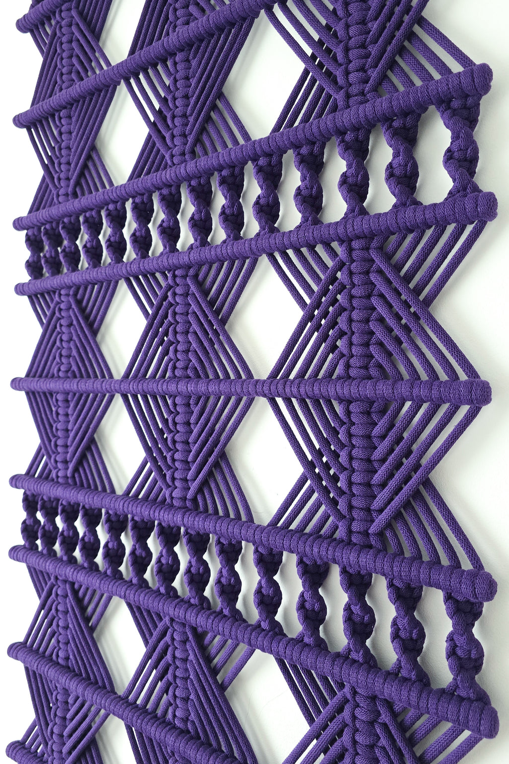 Zbliżenie geometrycznych splotów fioletowej makramy ściennej VELVET LINE NORDART