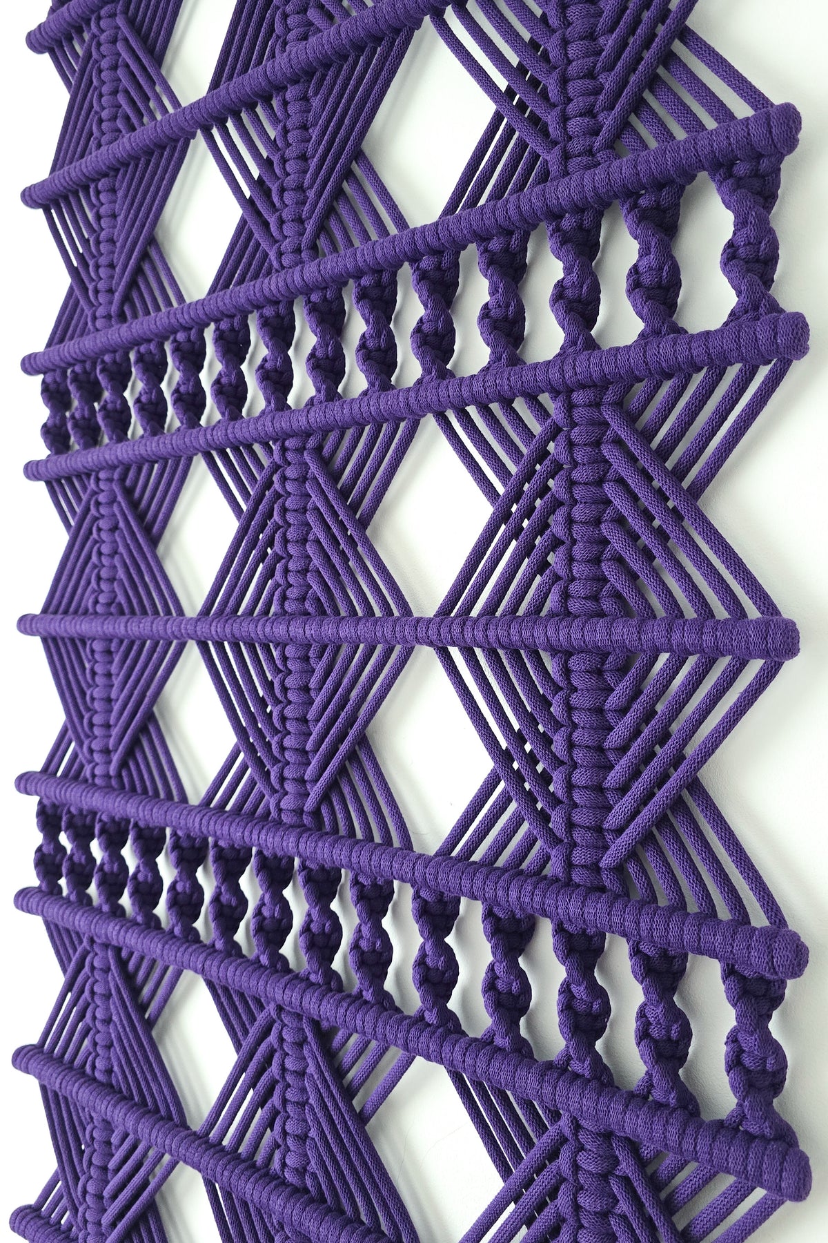 Zbliżenie geometrycznych splotów fioletowej makramy ściennej VELVET LINE NORDART